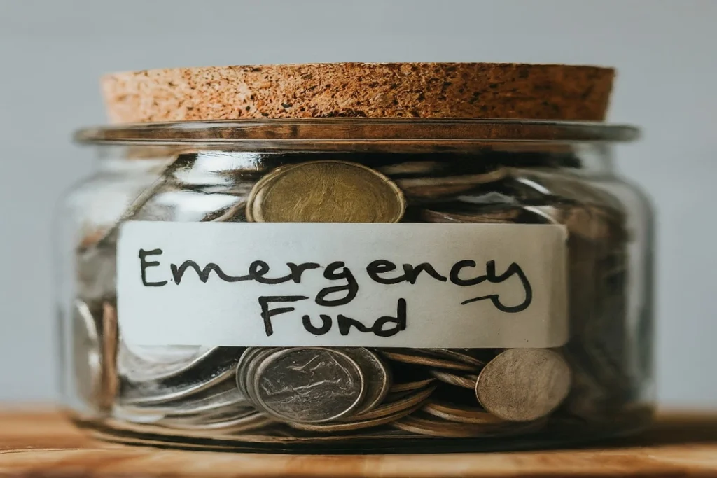 A jar labeled "Emergency Fund" filled with coins.